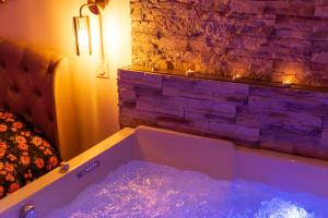 a bath tub with lights in front of a brick wall at Spa Edelweiss in Dijon