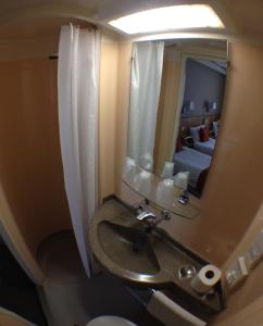 uma casa de banho com um lavatório e um espelho grande em Columbus Hotel em Londres