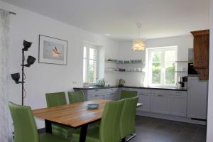 a kitchen with a wooden table and green chairs at wassernahes Ferienhaus mit Meerblick in ruhiger Lage - Ferienhaus Rohrweihe in Gager