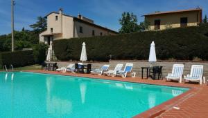 a swimming pool with chairs and tables and umbrellas at Agriturismo Le Ginestruzze in Montespertoli