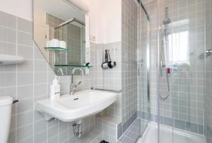 un bagno bianco con lavandino e doccia di Sylter Wohlfühlnest, App 2 a Wenningstedt