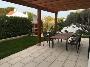 a patio with a wooden table and chairs under a pergola at Villa Blanca Punta Grossa in Punta Grossa