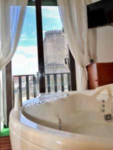 ナポリにあるコーボ デッリ ホテルの大きな窓のある客室で、バスタブが備わります。