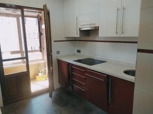 d'une cuisine avec des placards blancs, un évier et une fenêtre. dans l'établissement Apartamento Argandona-Gijon, à Gijón