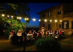 um grupo de pessoas sentadas a mesas num jardim à noite em Agriturismo Le Ginestruzze em Montespertoli