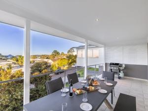 a dining room with a table and chairs on a balcony at Jackson View luxury holiday property with water views in Salamander Bay