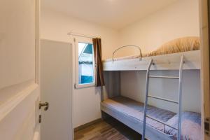 a room with two bunk beds and a door at Camping Arcobaleno in Marina di Bibbona