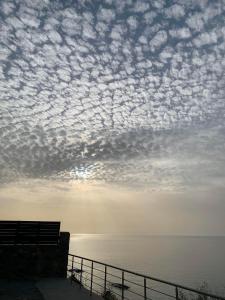 een bewolkte lucht boven het water met een bank bij House Gylisma in Kámbos