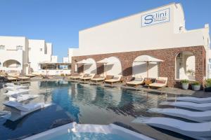 a swimming pool with lounge chairs in front of a building at Selini Ηotel in Kamari