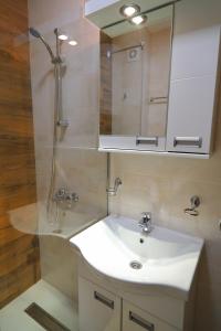 ソコバニャにあるApartman Alegroの白い洗面台と鏡のあるバスルーム
