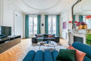 ein Wohnzimmer mit einem blauen Sofa und einem TV in der Unterkunft Sweet Inn - Rue de Cerisoles in Paris