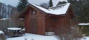 uma pequena cabana de madeira com neve no telhado em Woodhouse Spreewiesen em Burig