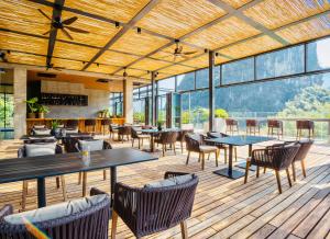 a restaurant with tables and chairs on a wooden deck at LUX* Chongzuo, Guangxi Resort & Villas in Daxin