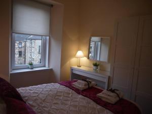 a bedroom with a bed and a lamp and a window at Fabulous location, One Bedroom West End Flat, just off Byres rd, close to SEC & Hydro in Glasgow