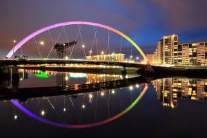 a bridge with a reflection in the water at night at Fabulous location, One Bedroom West End Flat, just off Byres rd, close to SEC & Hydro in Glasgow