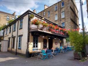 a building with a balcony with tables and chairs at Fabulous location, One Bedroom West End Flat, just off Byres rd, close to SEC & Hydro in Glasgow