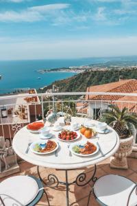 a white table with plates of food on a balcony at Etna Apartment in Taormina