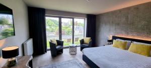 een hotelkamer met een bed en een groot raam bij Hôtel WELLNESS EAU DE ROCHE Durbuy in Durbuy