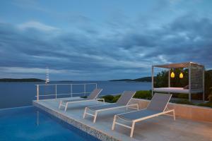 a couple of chairs sitting on the edge of a pool at Villa Roca in Vis