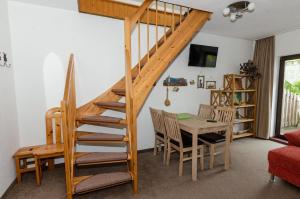 ein Wohnzimmer mit einer Holztreppe sowie einem Tisch und Stühlen in der Unterkunft 3 Raum FeWo auf Rügen für 4 Personen in Schaprode