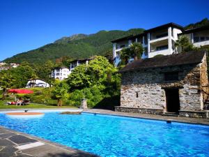a swimming pool in front of a building at 1 Zimmer Apartment mit Seesicht und Pool in Vira