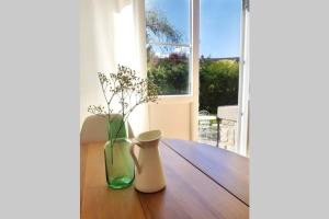 two vases sitting on a wooden table in front of a window at Le Petit Nicolas in Les Andelys