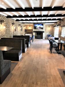 a large room with tables and couches and a tv at Cotswold Merrymouth Inn in Bourton on the Water