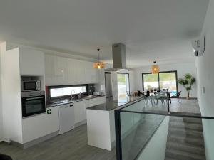 cocina con armarios blancos y comedor en Cairnvillas: Villa Terra C39 - Luxury Villa with Private Swimming Pool near Beach en Aljezur