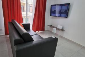 a living room with a black couch and a flat screen tv at SeaView 2 Double Bedroom Modern APARTMENT in St Paul's Bay