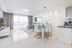 a white kitchen and dining room with a table and chairs at Stylish Vacation Apartment with Parking in Międzyzdroje by Renters in Międzyzdroje