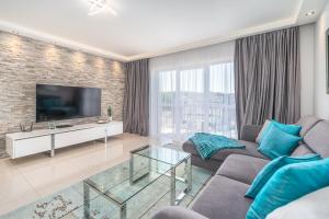 a living room with a couch and a tv at Stylish Vacation Apartment with Parking in Międzyzdroje by Renters in Międzyzdroje