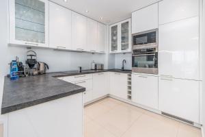 a white kitchen with white cabinets and appliances at Stylish Vacation Apartment with Parking in Międzyzdroje by Renters in Międzyzdroje