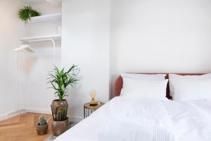 um quarto com uma cama com lençóis brancos e plantas em Trendy 2 bedroom accommodation on perfect location em Amsterdã