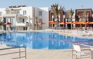 duży basen z krzesłami i pomarańczowymi parasolami w obiekcie Andalucia appart hoteL w mieście Bizerta