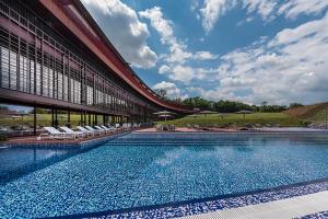 een groot zwembad met stoelen en een gebouw bij Villaverde Hotel Spa&Golf Udine in Fagagna