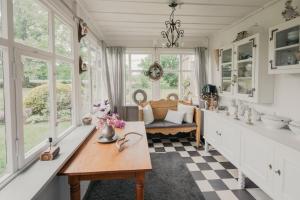 eine Küche mit einem Tisch, einem Sofa und Fenstern in der Unterkunft Charlottes Pfarrgarten in Niesky