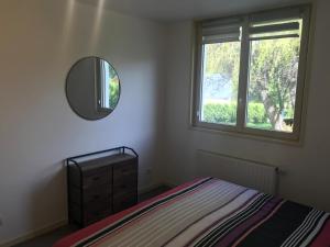 1 dormitorio con cama, espejo y ventana en La crémaillère, en Murol