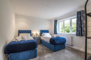 two beds in a bedroom with blue chairs and a window at Martello View - 3 Bedroom Holiday Home - Llanreath in Pembroke Dock