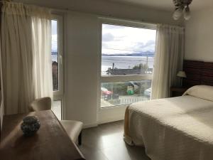 a bedroom with a large window with a view of the beach at Araucaria in San Carlos de Bariloche