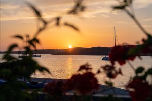 a sunset over a body of water with boats at Stella Hotel in Parikia