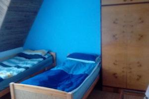 - 2 lits jumeaux dans une chambre avec un mur bleu dans l'établissement Gospodarstwo Agroturystyczne U Nos Apartament Bioły, à Ratułów