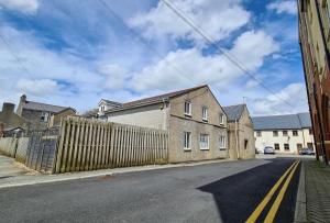 eine leere Straße mit einem Zaun und einem Haus in der Unterkunft Contractor & Leisure Stays- FREE Parking with Great Location in Pembrokeshire