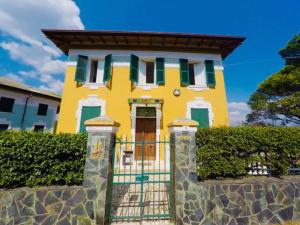 a yellow house with green shutters and a gate at Splendido Appartamento Vista Mare in Celle Ligure