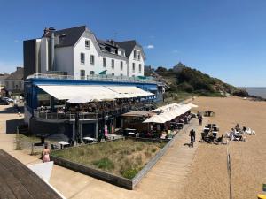 a building on the beach with people sitting on the sand at Résidence Fort de l'Eve - T2 à 380m plage M Hulot et commerces - St Marc sur Mer idéal famille proche La Baule P0rnichet avec parking privé in Saint-Nazaire