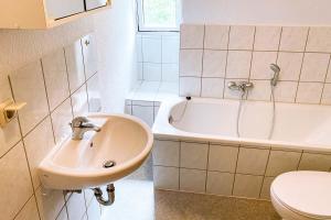 a bathroom with a sink and a tub and a toilet at Worker Apartments Bernsdorf-Wiednitz in Bernsdorf