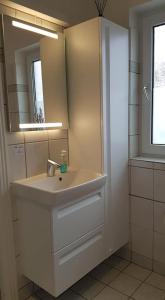 a white bathroom with a sink and a mirror at Løkken centrum ferielejlighed-apartment 4F in Løkken