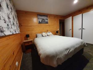 ein Schlafzimmer mit einem großen Bett und Holzwänden in der Unterkunft Folia Domus NZ, Redwoods, MBT in Rotorua