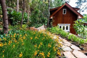 a garden with flowers in front of a cabin at Mooi Lake House Luxury Villa in Malabar