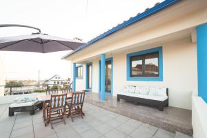 een patio met een tafel en stoelen en een parasol bij Viana Fishers House - Amazing Apartments in Front of the Sea in Viana do Castelo