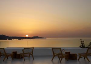a group of chairs sitting on a patio with a sunset at Domes White Coast Milos, Adults Only - Small Luxury Hotels of the World in Mytakas